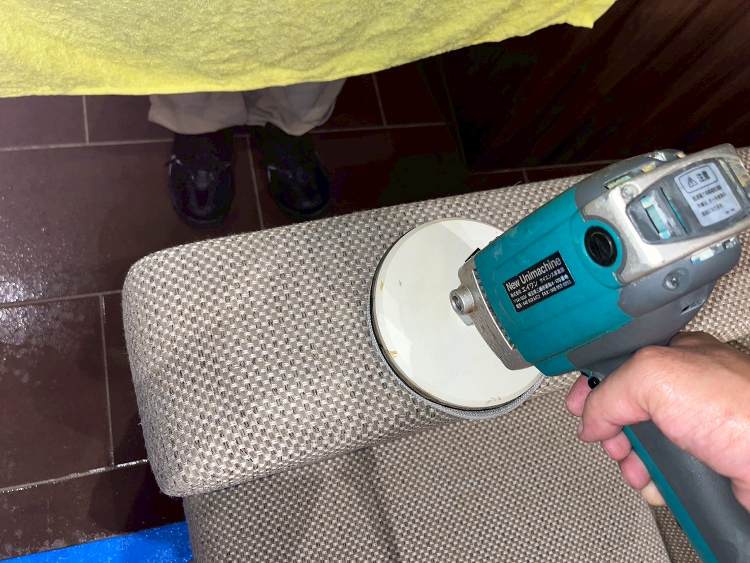 電動ポリッシャーを使ってソファーのクレヨン汚れを丁寧にクリーニングしている様子